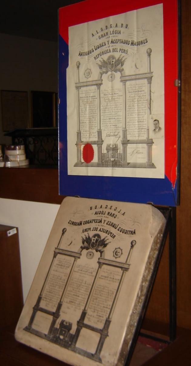 Prensa litográfica donada por la R.·.L.·.S.·. Cruz Austral N° 12. Corresponde al sello con que se imprimían los diplomas de M.·. M.·. (parte inferior); en la parte superior se tiene un diploma de M.·. M.·. impreso con dicha matriz en 1930 E.·.V.·.